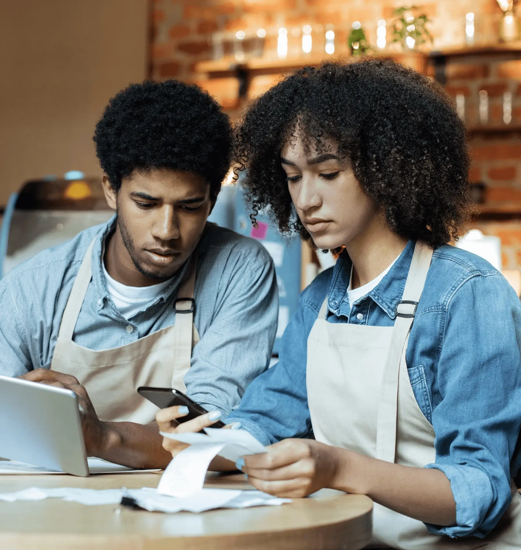 Two workers reviewing receipts and using a tablet